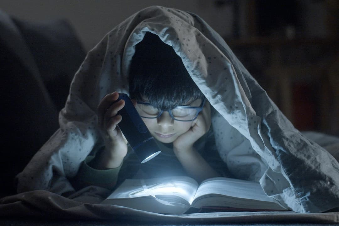 kid reading a book at night